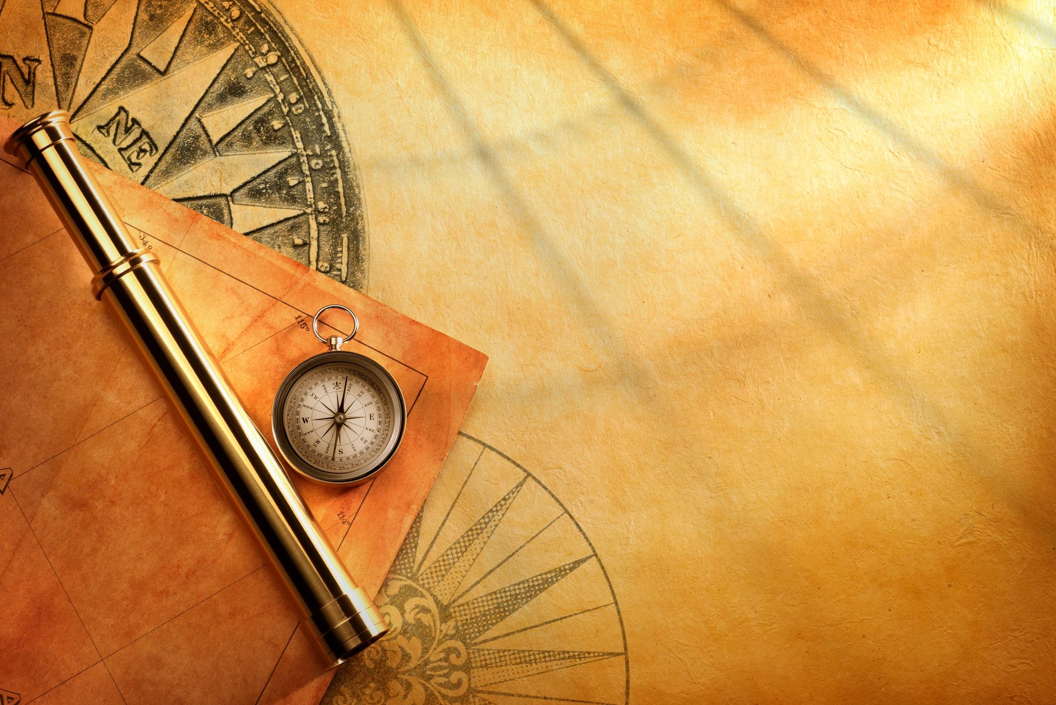 Compass and spyglass on an old treasure map