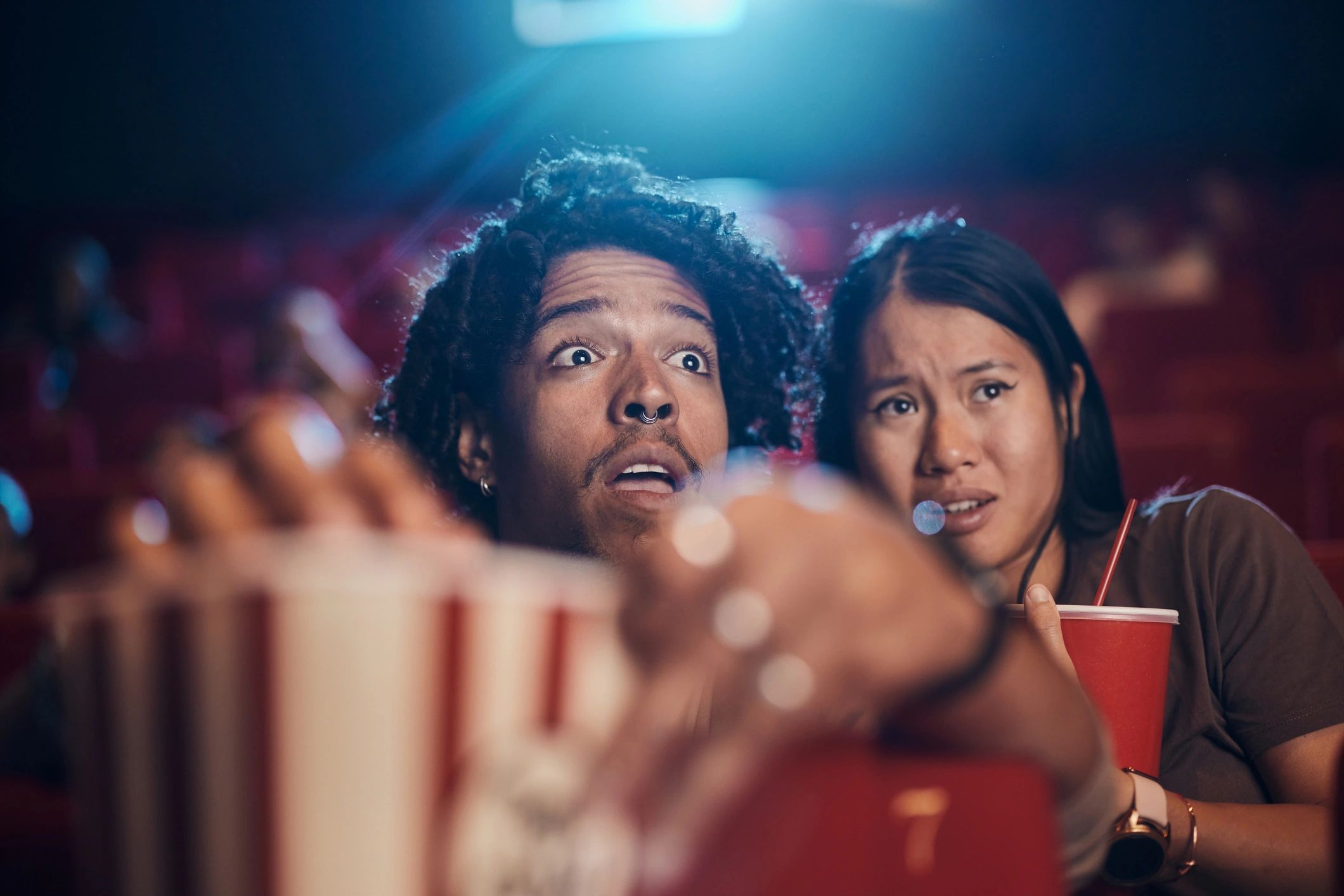 Couple reacting to a suspenseful detective movie in a cinema