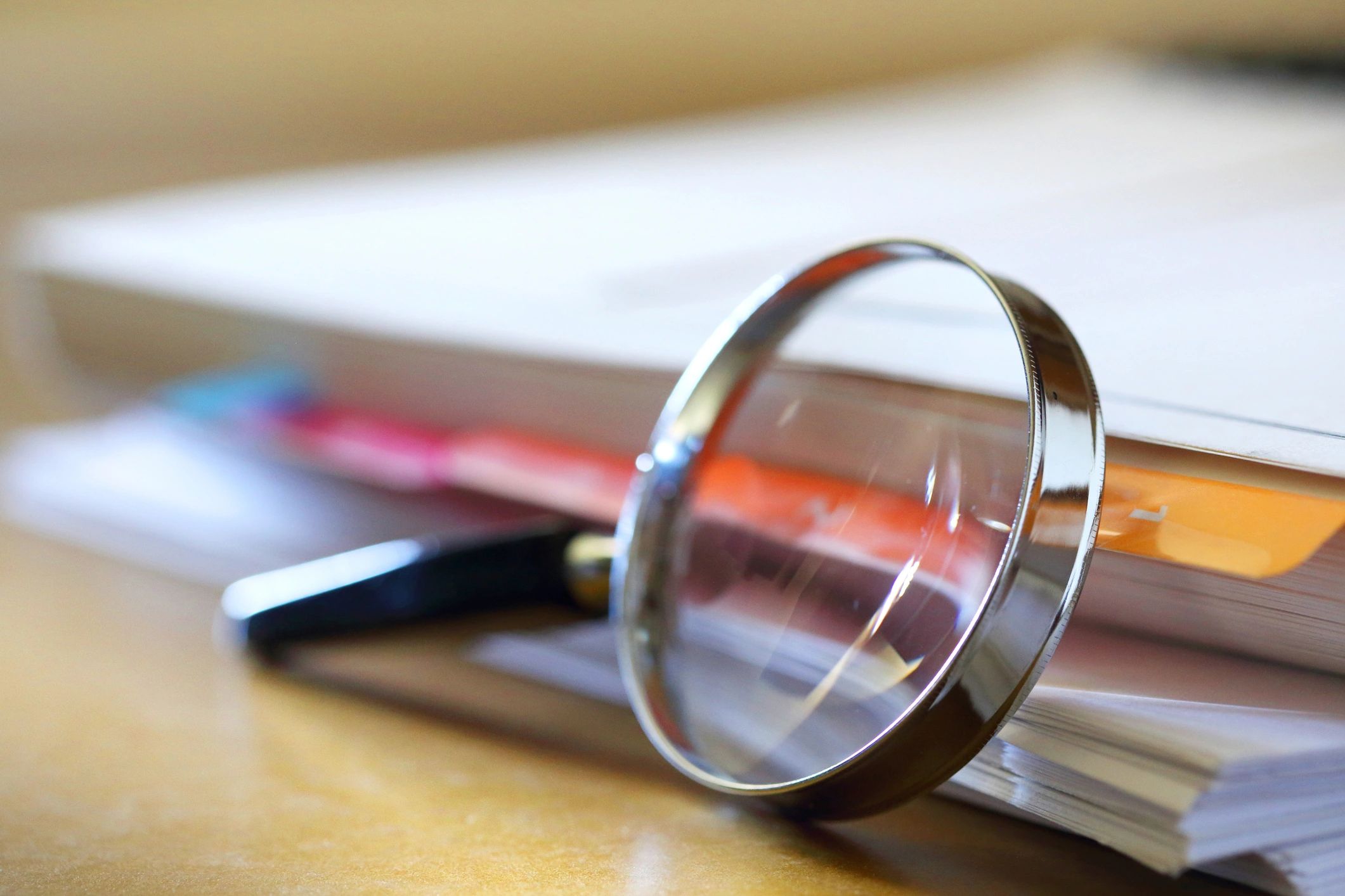 Magnifying glass leaning against a stack of papers