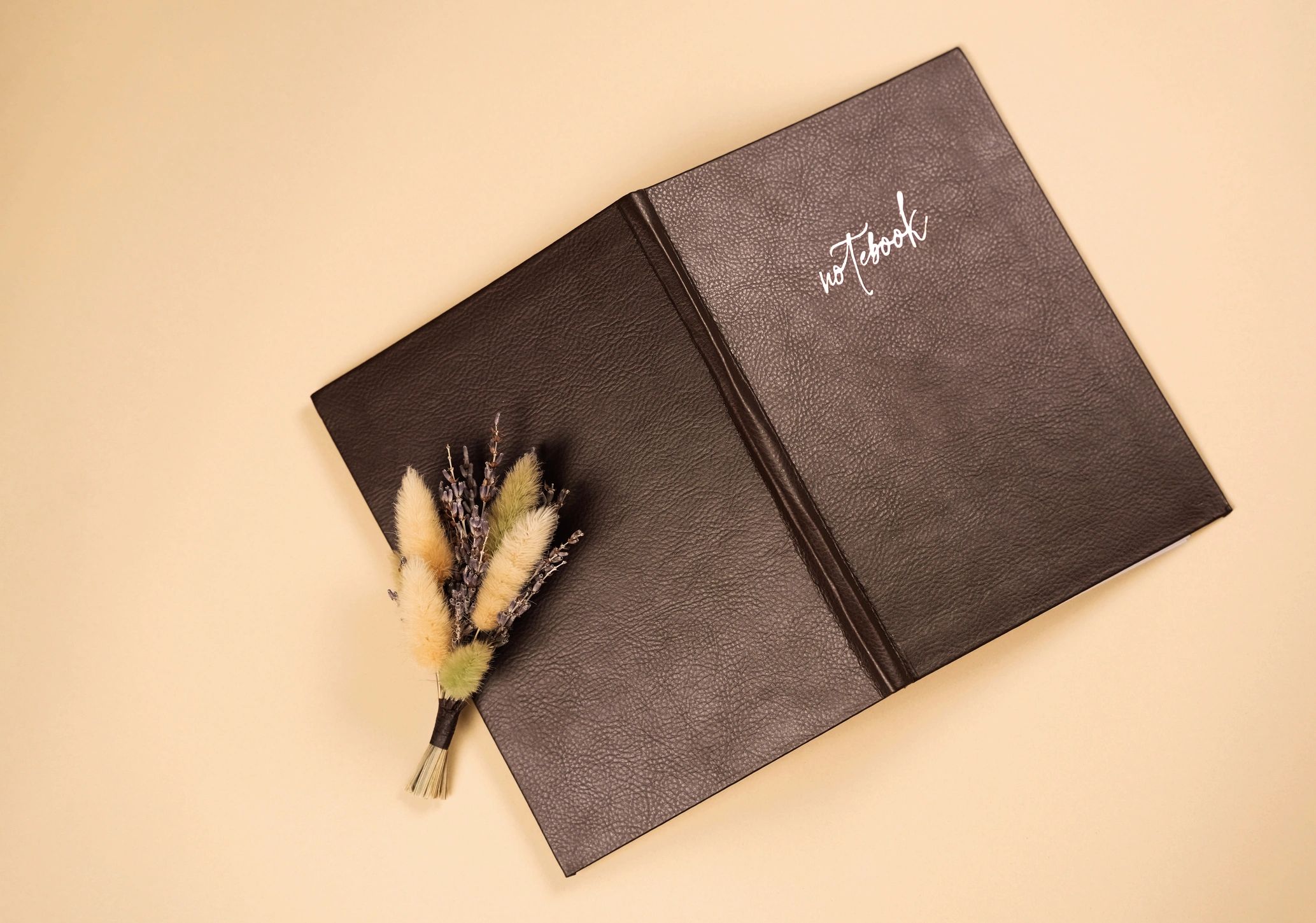 Leather notebook with dried flowers on a neutral background