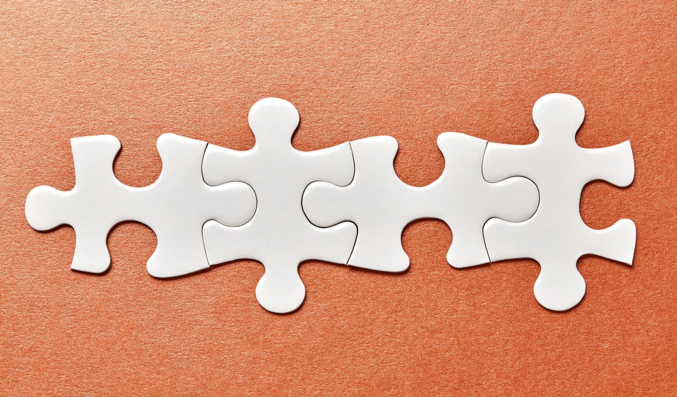 Connected white jigsaw puzzle pieces on orange background