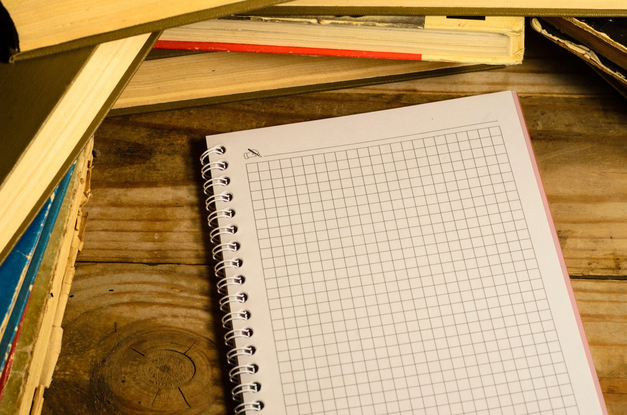 Notepad and glasses in front of many books